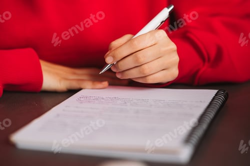 Preview: Close-up woman's hand holding a pencil and writing information in a notebook