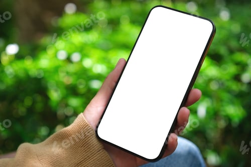 Preview: Mockup image of a woman holding mobile phone with blank white desktop screen in the outdoors