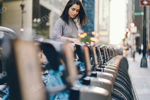 Preview: girl renting a city bike from a bike stand
