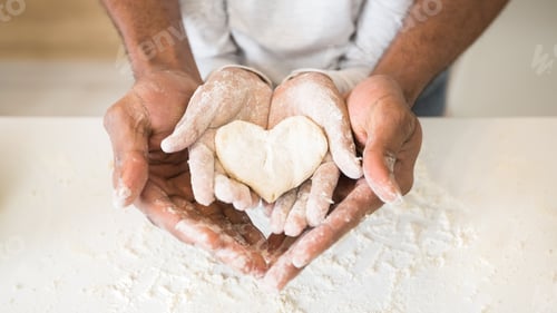 Preview: Afro man hands holding child hands with heart shaped pastry
