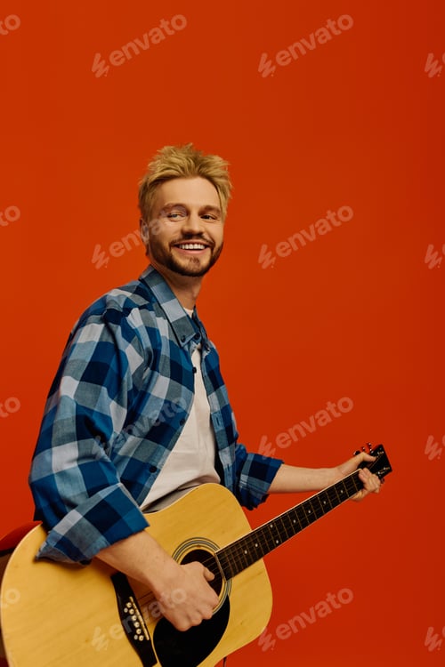 Preview: Smiling young man strums guitar strings, enjoying the moment with passion and energy