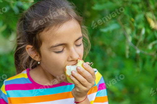 Preview: The child eats an apple in the garden. Selective focus.