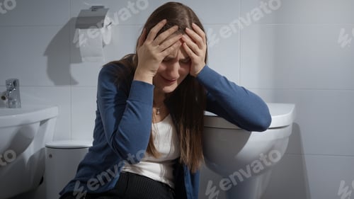 Preview: Young upset woman sitting in toilet and crying. Victim of home violence. Female depression.