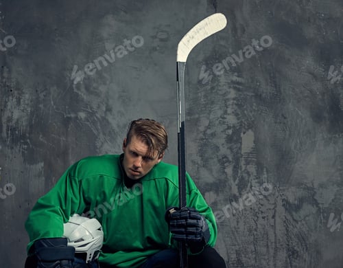 Preview: Hockey player wearing black protective uniform holds a hockey stick on a gray background.