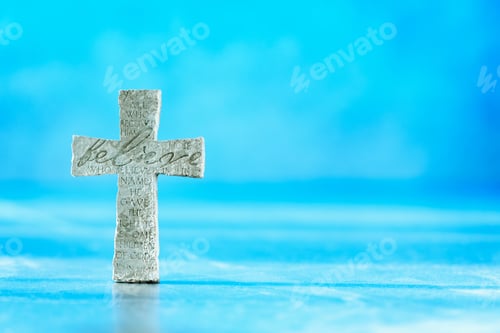 Preview: Stone cross with inscription Believe on blue background, Copy space. Christian backdrop. Biblical