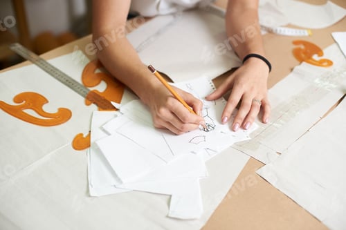 Preview: Workplace in modern design studio. Female designer creating exclusive flat paper clothing patterns.