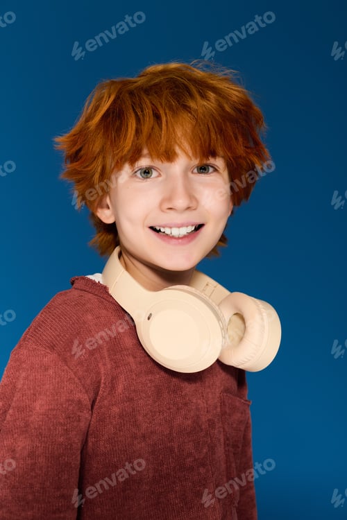 Preview: Redhead boy showcases trendy child fashion in a vibrant studio setting