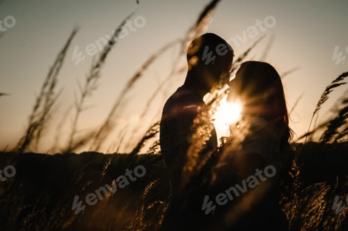Preview: Silhouette young couple hugging and kissing in autumn at an outdoor on park on the background field,