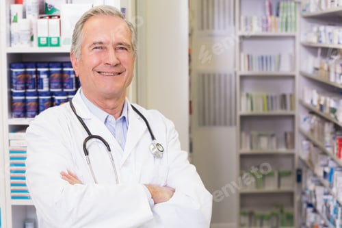 Preview: Senior male doctor wearing white coat and stethoscope standing amid medication shelves, copy space