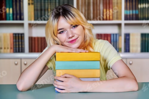 Preview: Female teenage high school student looking at camera with books in library