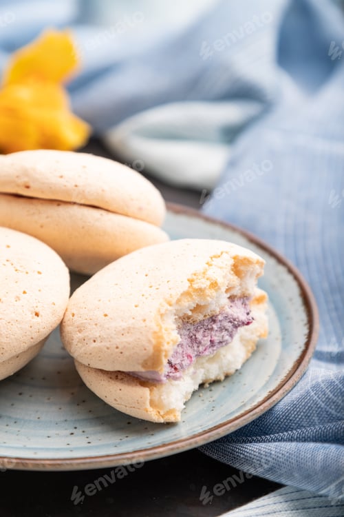 Preview: Meringues cakes with cup of coffee on a black concrete background. Side view, selective focus.
