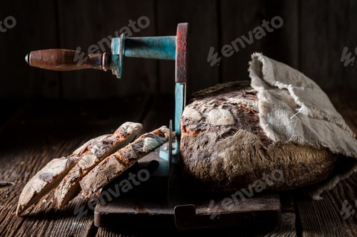 Preview: Loaf of bread on slicer with crumbs and flour