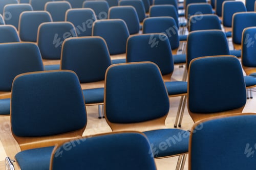 Preview: Rows of blue chairs stand in empty hall creating calm geometric pattern.