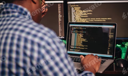 Preview: African American man sitting at computer desk looking at computer code, programming, developer