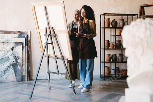 Preview: Mature teacher talking with her student during class in art school