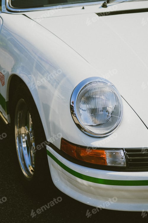 Preview: Vertical shot of a white vintage car parked outdoors on a sunny day