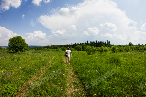 Preview: Rear view of young male hiker hiking along rural dirt track