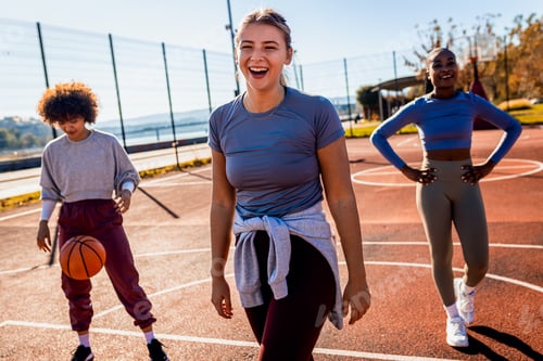 Preview: Diverse group of young woman having fun playing recreational basketball outdoors.