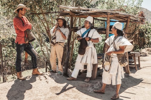 Vista previa: Un grupo de hombres indígenas arhuacos charlan relajadamente entre sí rodeados de naturaleza.
