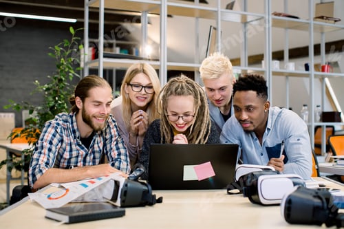 Preview: Group of young diverse multiracial designers working as team in modern creative office. Young people