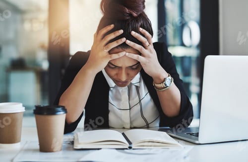 Preview: Shot of a young businesswoman looking stressed while working at her desk in a modern office