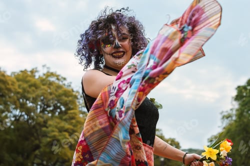 Preview: happy latin young woman with catrina makeup practicing folkloric dance in the park