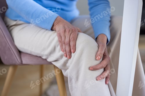 Preview: Senior woman sitting holding knee feeling joint pain