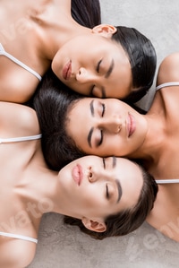 Preview: top view of charming female multiethnic friendship lying with closed eyes