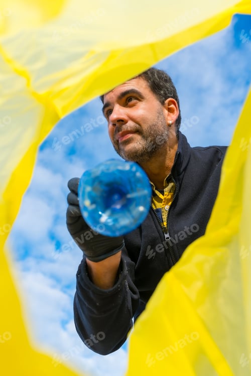 Preview: Man picking up trash on the beach. Ecology, sea pollution, cleaning the sand from plastics