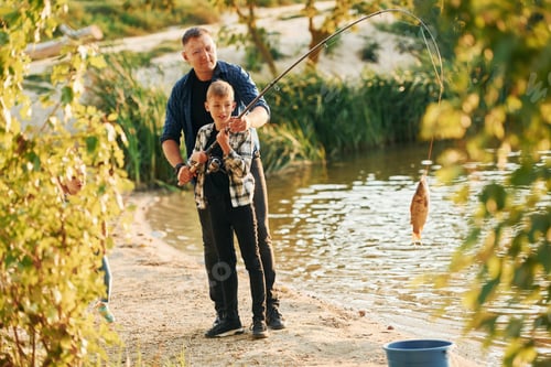 Preview: Holding the catch. Father and son on fishing together outdoors at summertime