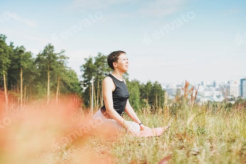 Preview: Young smiling woman practice yoga outdoors in the city. New normal social distance