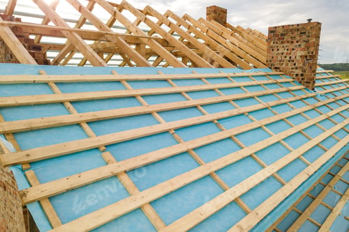 Preview: Aerial view of a brick house with wooden roof frame under construction.