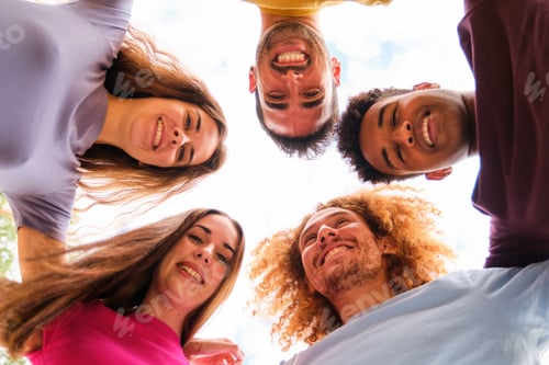Preview: Low angle view of multiracial friends together in a circle at street.
