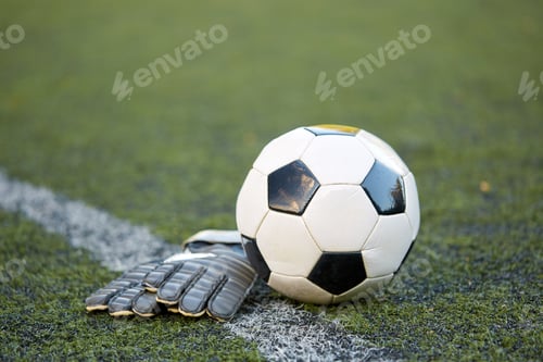 Preview: soccer ball and goalkeeper gloves on field