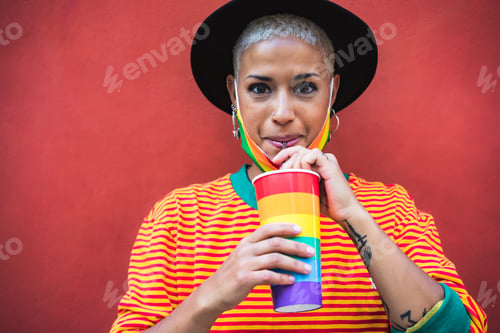 Preview: Young woman drinking cocktail during gay pride parade - LGBT community concept