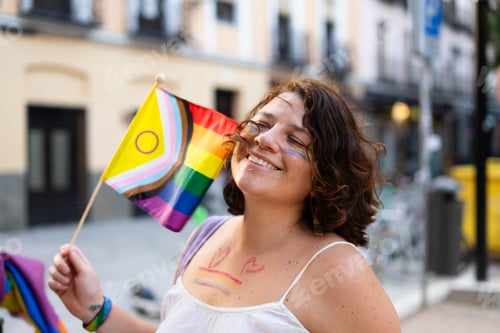 Preview: woman waving intersex-inclusive progress pride flag at a pride parade