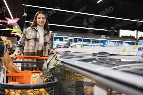 Preview: Portrait of beautiful young woman with a shopping trolley at supermarket