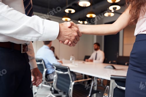 Preview: Close Up Of Businessman And Businesswoman Shaking Hands In Modern Boardroom