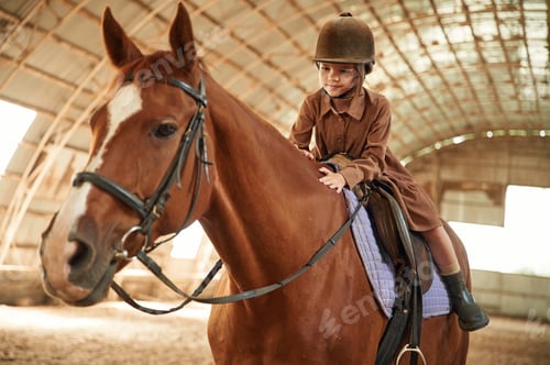 Preview: Riding the animal. Cute little girl is with horse indoors