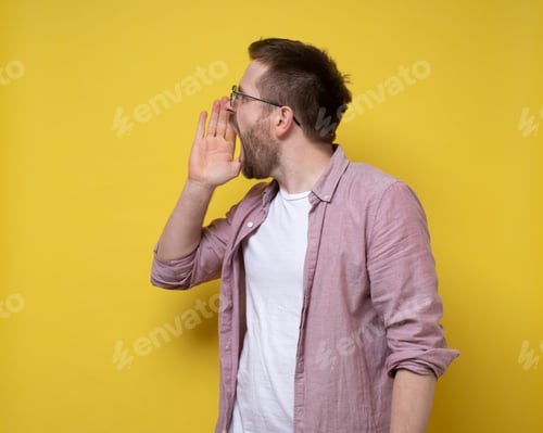 Vista previa: Young caucasian man in glasses screams loudly with his hand to his wide open mouth.