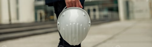 Preview: Close up of engineer in suit holding protective helmet and paper folder. Industrial concept