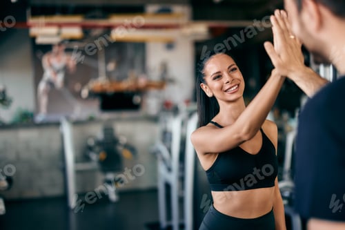 Preview: Focus on the smiling fit girl, giving a high five to her male partner, finishing a workout together.