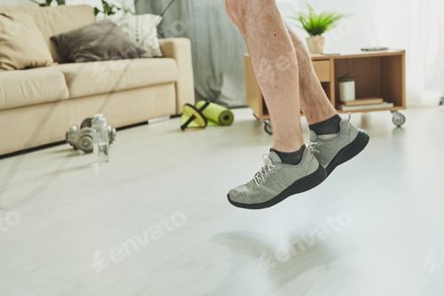 Preview: Lower part of young active man legs in sports shoes in jump over floor