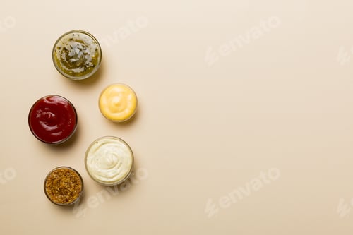 Preview: Different types of sauces in bowls on a colored Board . Top view. various sauces copy space