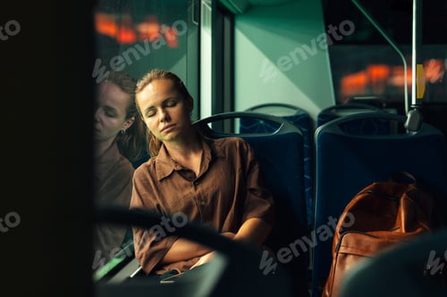 Preview: Tired urban commuter woman napping on bus at night.