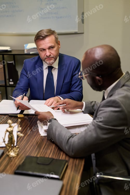Preview: Middle Aged Caucasian Man and Young Black Man Discussing Legal Documents