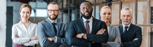 Preview: panoramic shot of multicultural businessmen and cheerful businesswomen standing with crossed arms