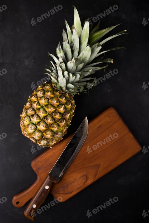 Preview: top view of pineapple with knife on cutting board on black background