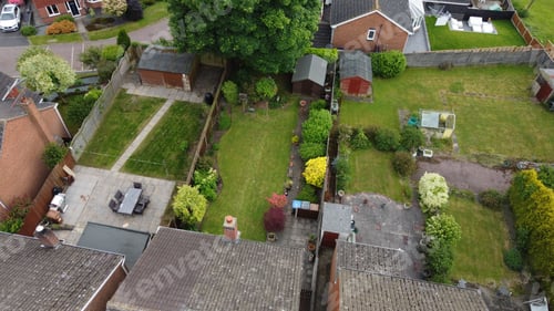 Preview: Residential backyards with green lawns, sheds, and patio furniture in a suburban neighborhood.