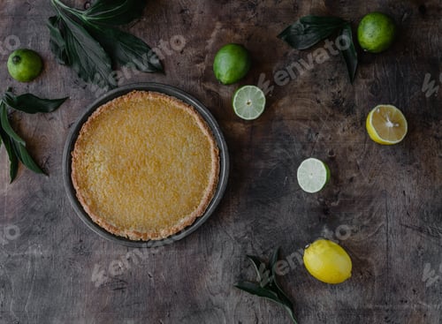 Preview: top view of tasty lemon pie and limes with lemons on wooden table